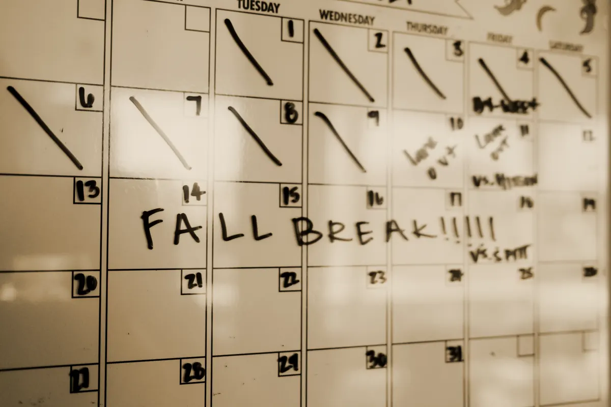 A whiteboard month planner with days struck through and games written in
