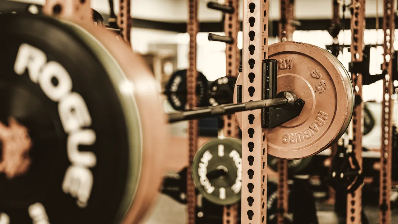 A loaded barbell resting in a squat rack, the upright marked with numbered holes