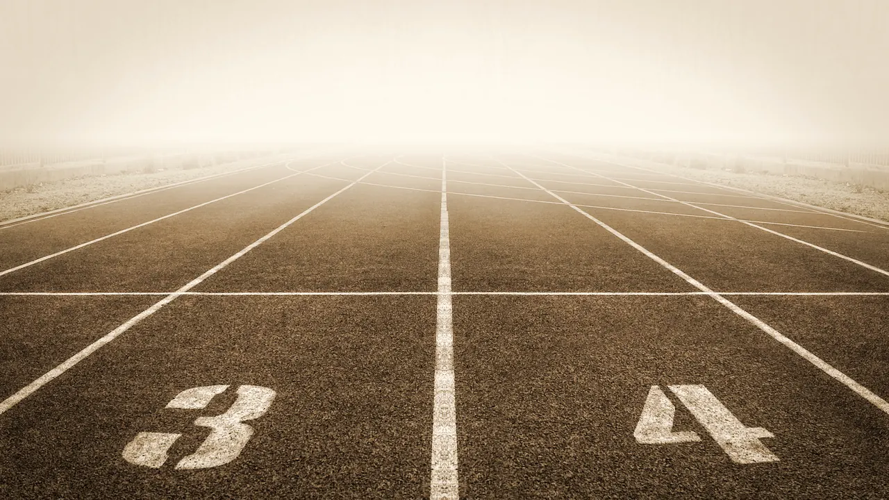 Numbered lanes on a running track disappearing into fog