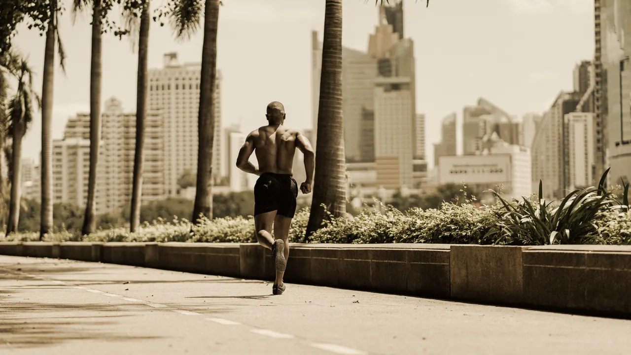 A runner seen from behind on an empty path, city towers beyond
