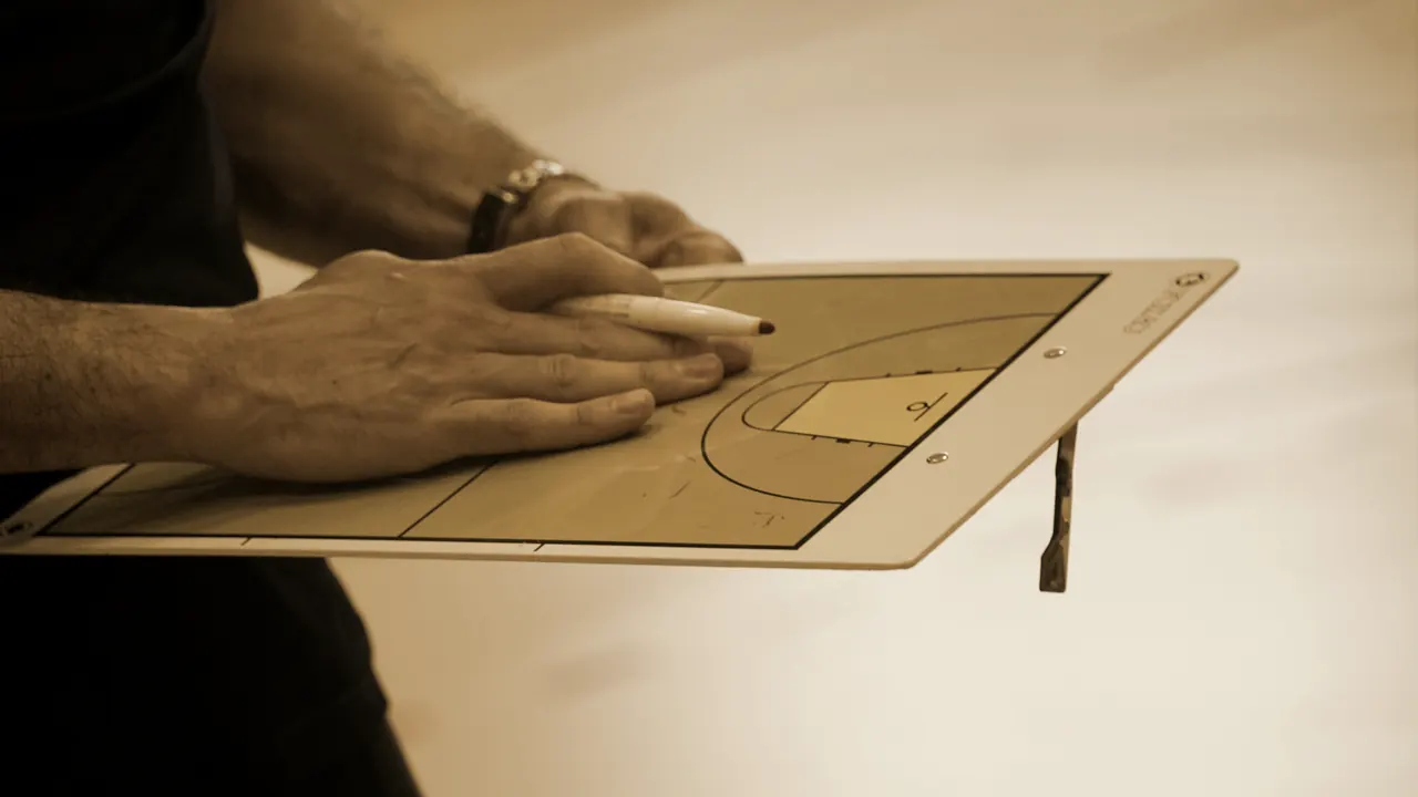 A coach marking a play onto a handheld tactics board