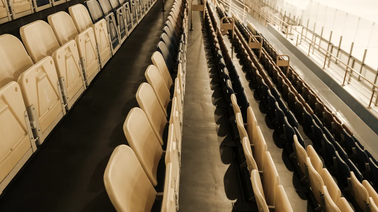 Empty rows of arena seating looking down toward the rink