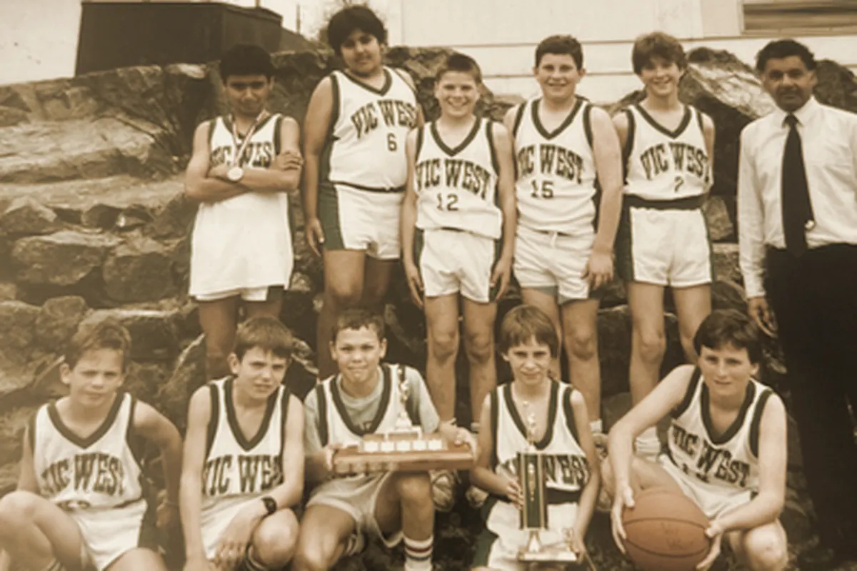 An archival team photograph of a youth basketball team in Vic West jerseys, posed with a trophy